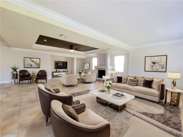 living room featuring ornamental molding, ceiling fan, a tray ceiling, and light tile patterned floors