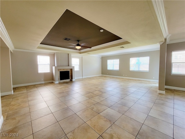 unfurnished living room featuring a wealth of natural light, ornamental molding, a tray ceiling, and ceiling fan