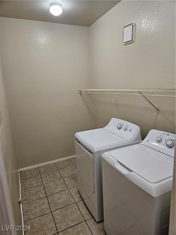 laundry room featuring a textured ceiling, washing machine and dryer, and light tile patterned floors