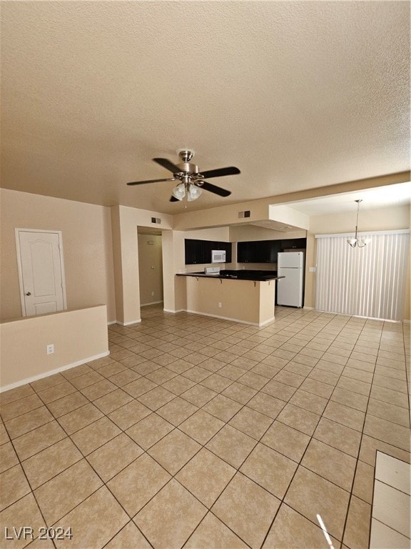 unfurnished living room with ceiling fan with notable chandelier, light tile patterned floors, and a textured ceiling