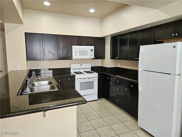 kitchen with white appliances, light tile patterned floors, kitchen peninsula, sink, and dark stone counters