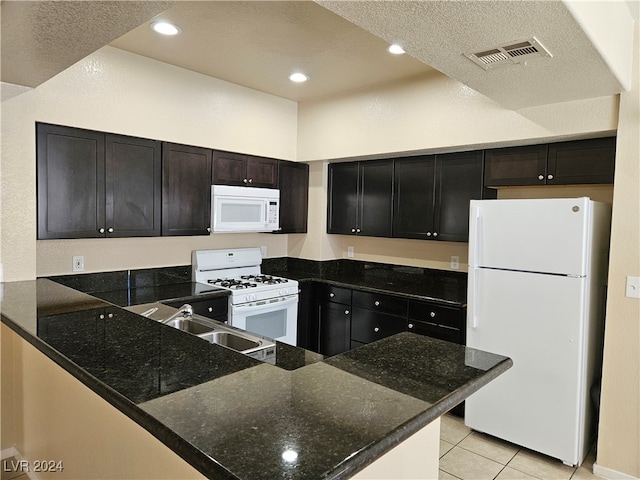 kitchen featuring white appliances, light tile patterned floors, kitchen peninsula, and a textured ceiling