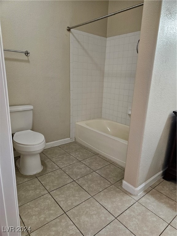 bathroom featuring tile patterned flooring, toilet, and tiled shower / bath combo