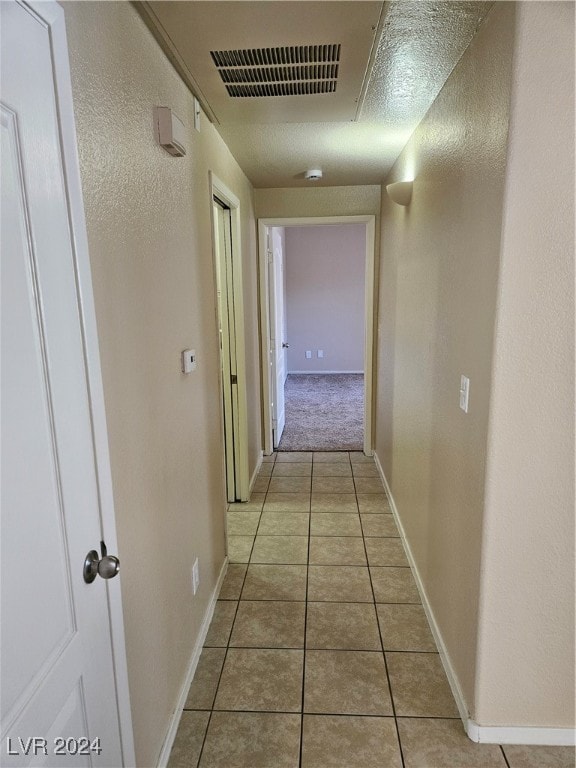 hallway featuring a textured ceiling and light tile patterned floors