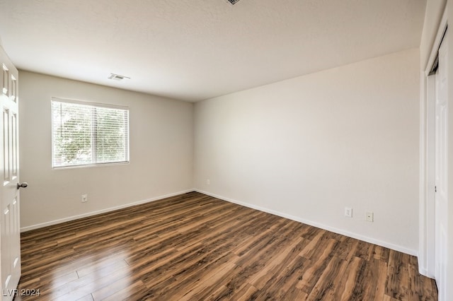 unfurnished bedroom featuring a closet, dark hardwood / wood-style flooring, and a textured ceiling