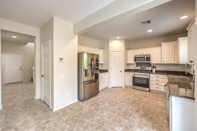 kitchen with dark stone counters, sink, appliances with stainless steel finishes, and white cabinetry