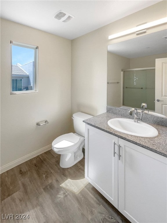 bathroom with vanity, toilet, wood-type flooring, and a shower with door