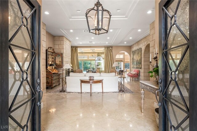 foyer entrance featuring crown molding, an inviting chandelier, and a tray ceiling