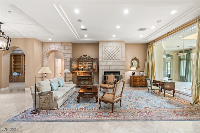 living room with a fireplace, a raised ceiling, and light tile patterned flooring