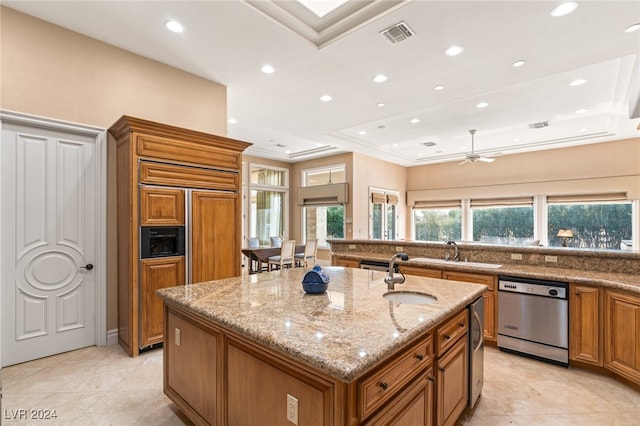 kitchen with a kitchen island with sink, dishwasher, sink, light stone countertops, and ceiling fan