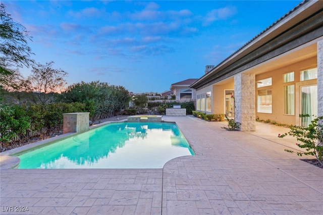 pool at dusk featuring a patio