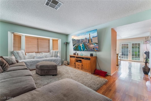 living room with wood finished floors, baseboards, visible vents, french doors, and a textured ceiling