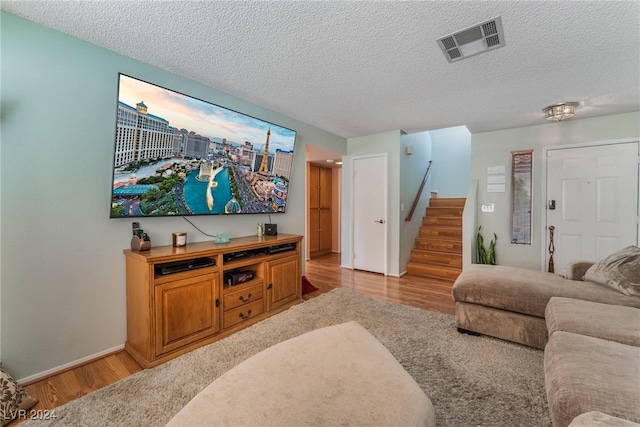 living room with a textured ceiling and light hardwood / wood-style floors