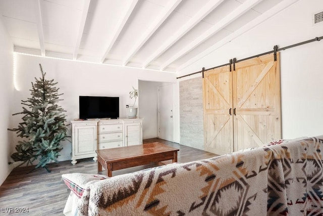 interior space with a barn door, wood finished floors, visible vents, and vaulted ceiling with beams