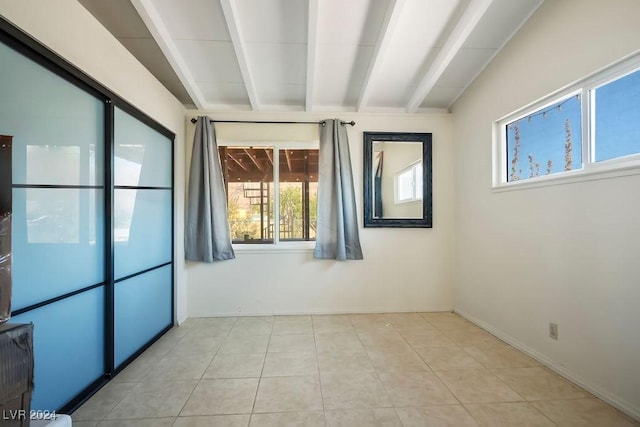 unfurnished room with baseboards, light tile patterned flooring, and beamed ceiling