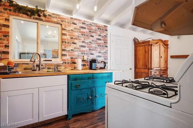 kitchen featuring dark wood finished floors, range hood, a sink, gas range gas stove, and brick wall