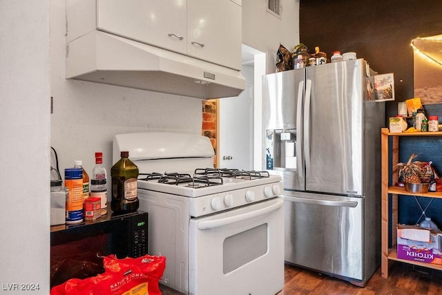 kitchen with stainless steel fridge, dark wood finished floors, under cabinet range hood, white range with gas cooktop, and visible vents