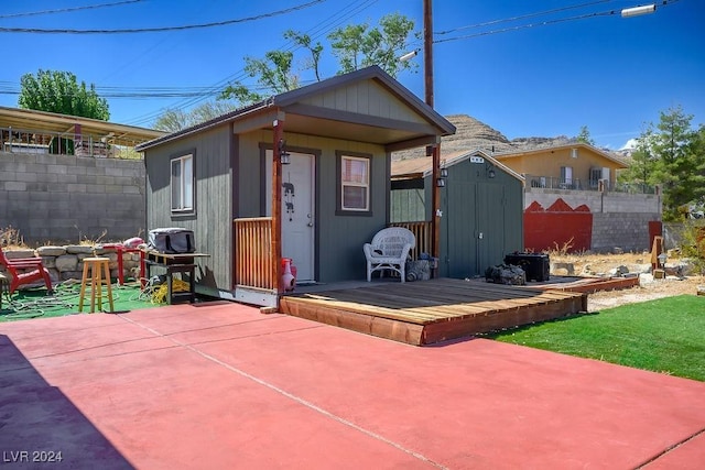 rear view of property featuring an outdoor structure, fence, and a patio area