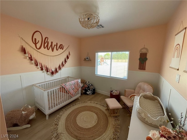 bedroom with a crib and hardwood / wood-style floors