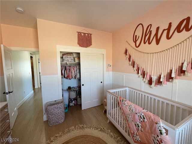 bedroom featuring a nursery area, hardwood / wood-style flooring, and a closet