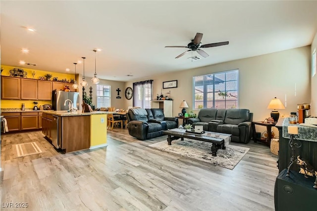 living room with ceiling fan, light hardwood / wood-style floors, and a healthy amount of sunlight