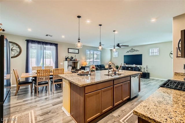 kitchen with a kitchen island with sink, sink, pendant lighting, and dishwasher