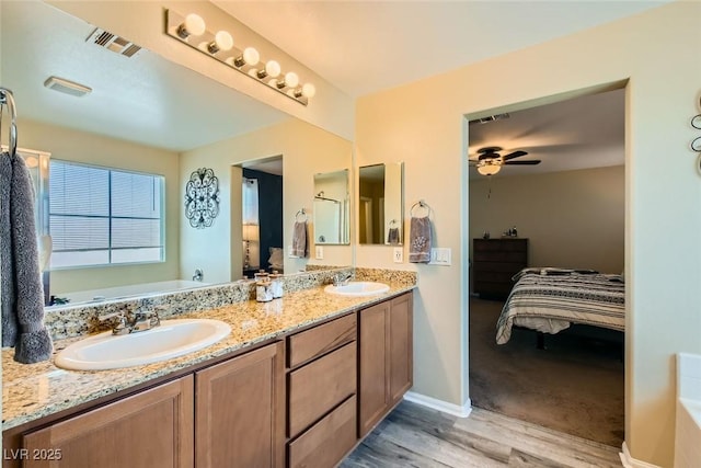 bathroom featuring ceiling fan, vanity, wood-type flooring, and a tub