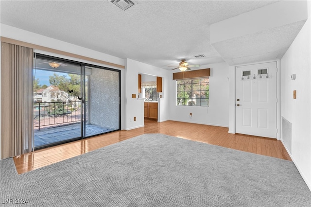 spare room with ceiling fan, a textured ceiling, and light hardwood / wood-style flooring