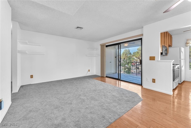 spare room featuring a textured ceiling, ceiling fan, and light hardwood / wood-style flooring