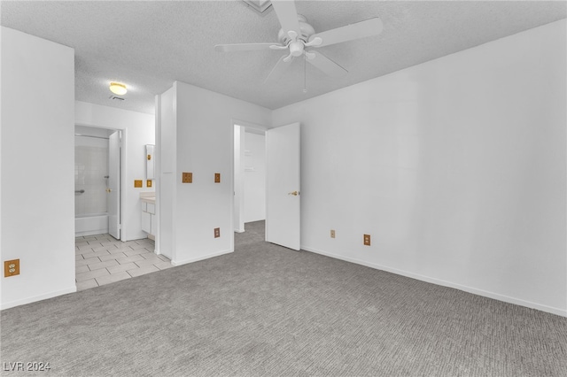 empty room with a textured ceiling, ceiling fan, and light colored carpet