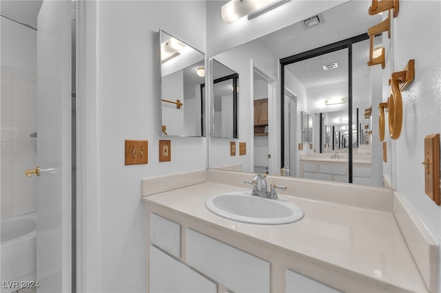 bathroom featuring a textured ceiling, vanity, and shower / washtub combination