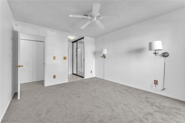 unfurnished bedroom with ceiling fan, light colored carpet, and a textured ceiling