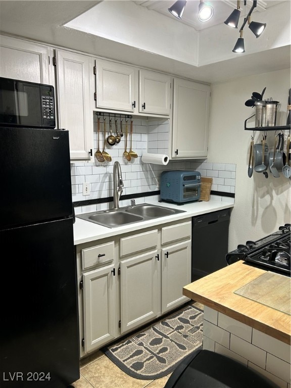 kitchen featuring sink, white cabinets, black appliances, and light tile patterned floors