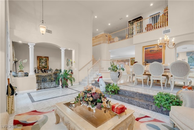 living room featuring light tile patterned floors, a high ceiling, decorative columns, and a notable chandelier