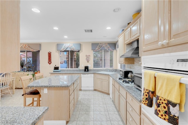 kitchen with ventilation hood, white appliances, a kitchen bar, and plenty of natural light