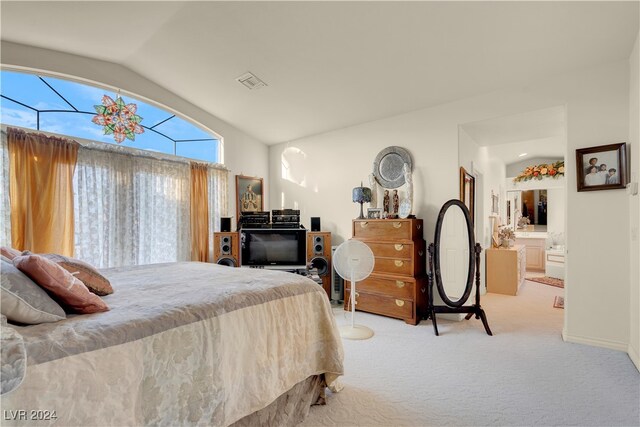 bedroom with vaulted ceiling, light carpet, and ensuite bathroom