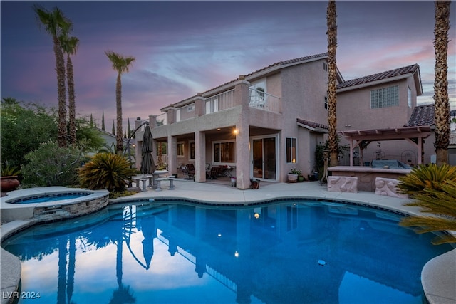 pool at dusk with a pergola, a patio area, and an in ground hot tub