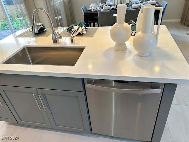 kitchen featuring gray cabinetry, sink, and stainless steel dishwasher