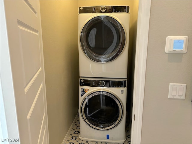 laundry area with stacked washing maching and dryer and tile patterned floors