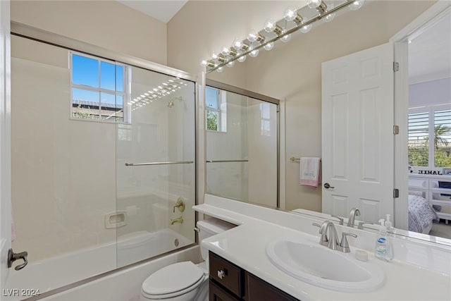 full bathroom with bath / shower combo with glass door, toilet, and vanity