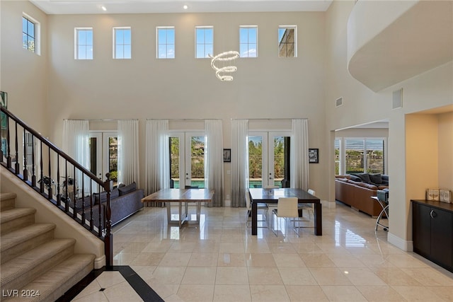 entrance foyer with a high ceiling, plenty of natural light, french doors, and light tile patterned floors