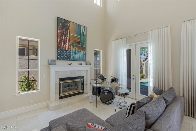 tiled living room with a towering ceiling, a high end fireplace, and french doors