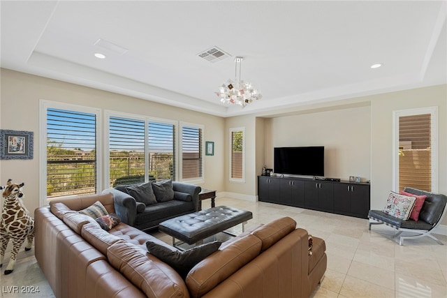 tiled living room featuring a tray ceiling and a chandelier