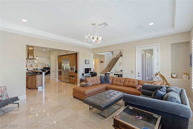 living room featuring an inviting chandelier and a raised ceiling