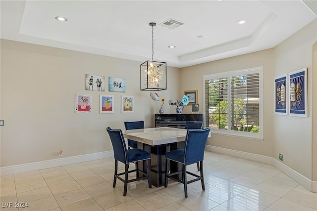 dining area featuring light tile patterned floors, a tray ceiling, and an inviting chandelier