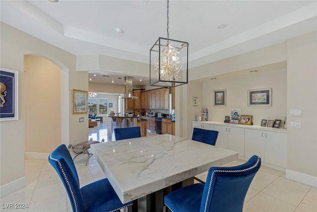 dining room featuring a tray ceiling, an inviting chandelier, and light tile patterned floors