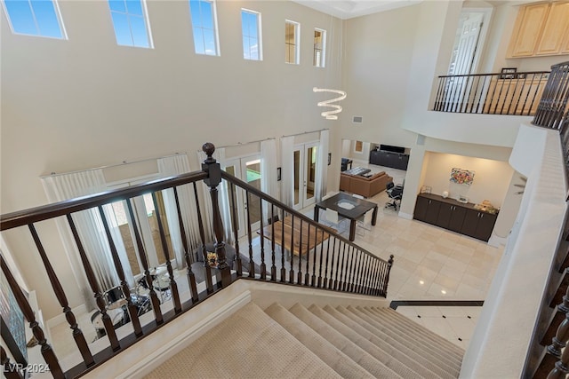 staircase with tile patterned floors, a towering ceiling, and a chandelier