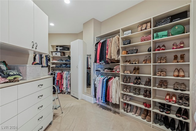 walk in closet featuring light colored carpet