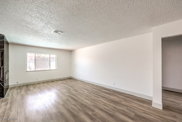 empty room featuring hardwood / wood-style floors, a textured ceiling, and a fireplace