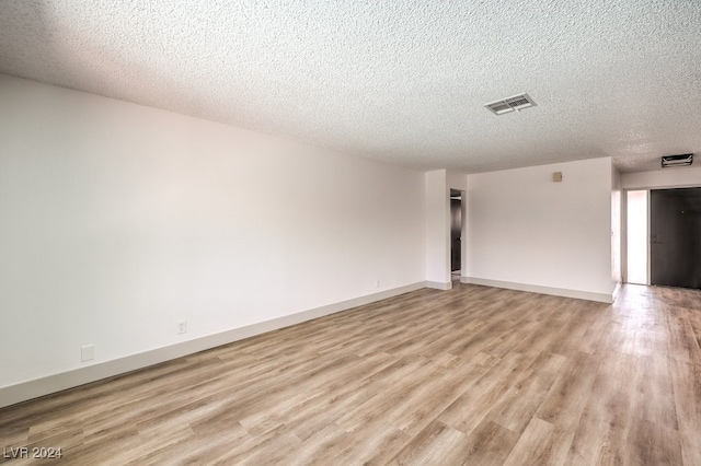 empty room featuring a textured ceiling and light hardwood / wood-style flooring